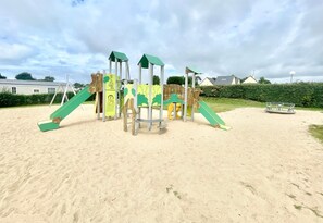 A playground with slides and climbing structures on sandy ground.