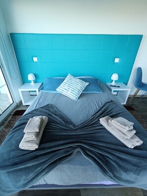 A bed with a teal headboard, two bedside tables with lamps, and a chair. - Bungalow 'Private House Ocean View - 2' with Shared Pool, Garden and Wi-Fi (Gaula)