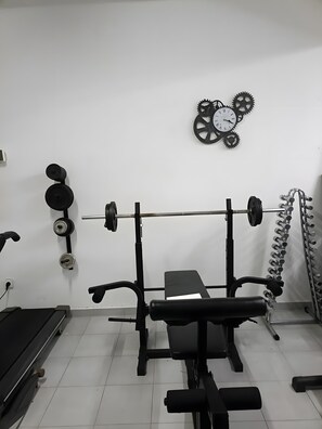 A gym with a bench press, squat rack, and various weights. - Bungalow 'Private House Ocean View - 2' with Shared Pool, Garden and Wi-Fi (Gaula)