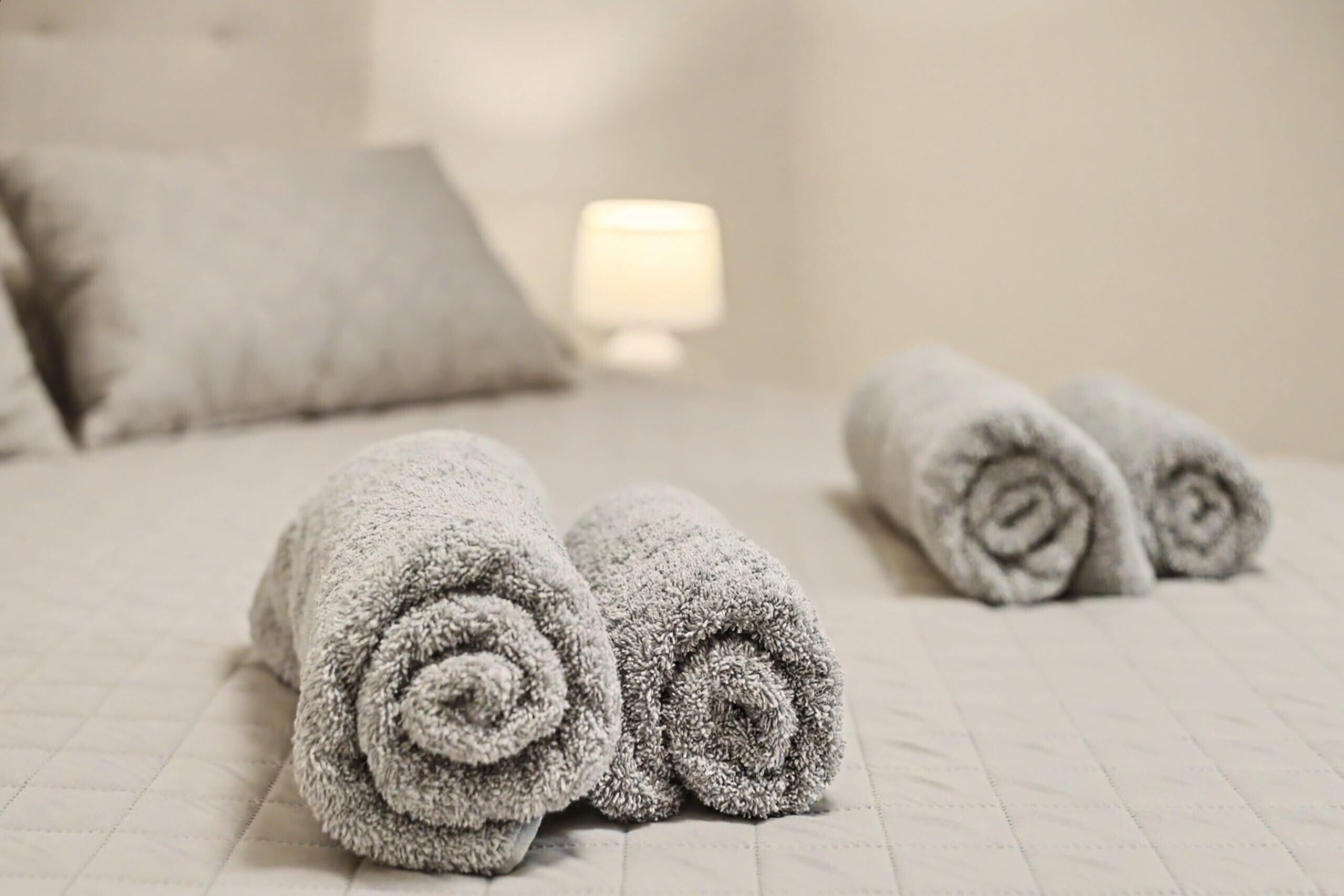 Ein Bett mit zusammengerollten Handtüchern und einer Nachttischlampe.