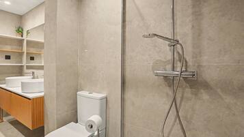 Un baño moderno con inodoro, lavamanos y ducha.