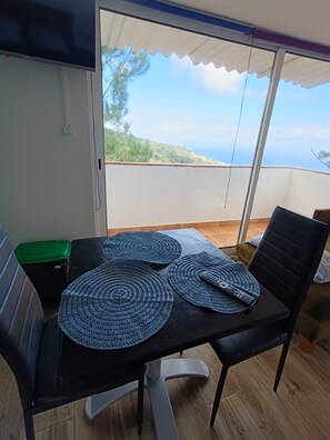Ein Balkon mit Tisch, Stühlen und Meerblick.