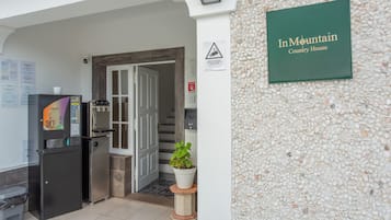 Zona de recepción con un cartel que dice 'En Mountain Country House', dispensador de agua, refrigerador y una planta en maceta.