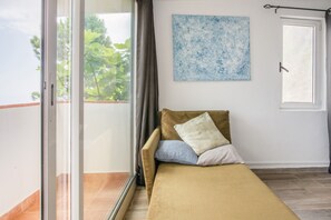 Een kamer met een bed, een raam en een schilderij aan de muur.