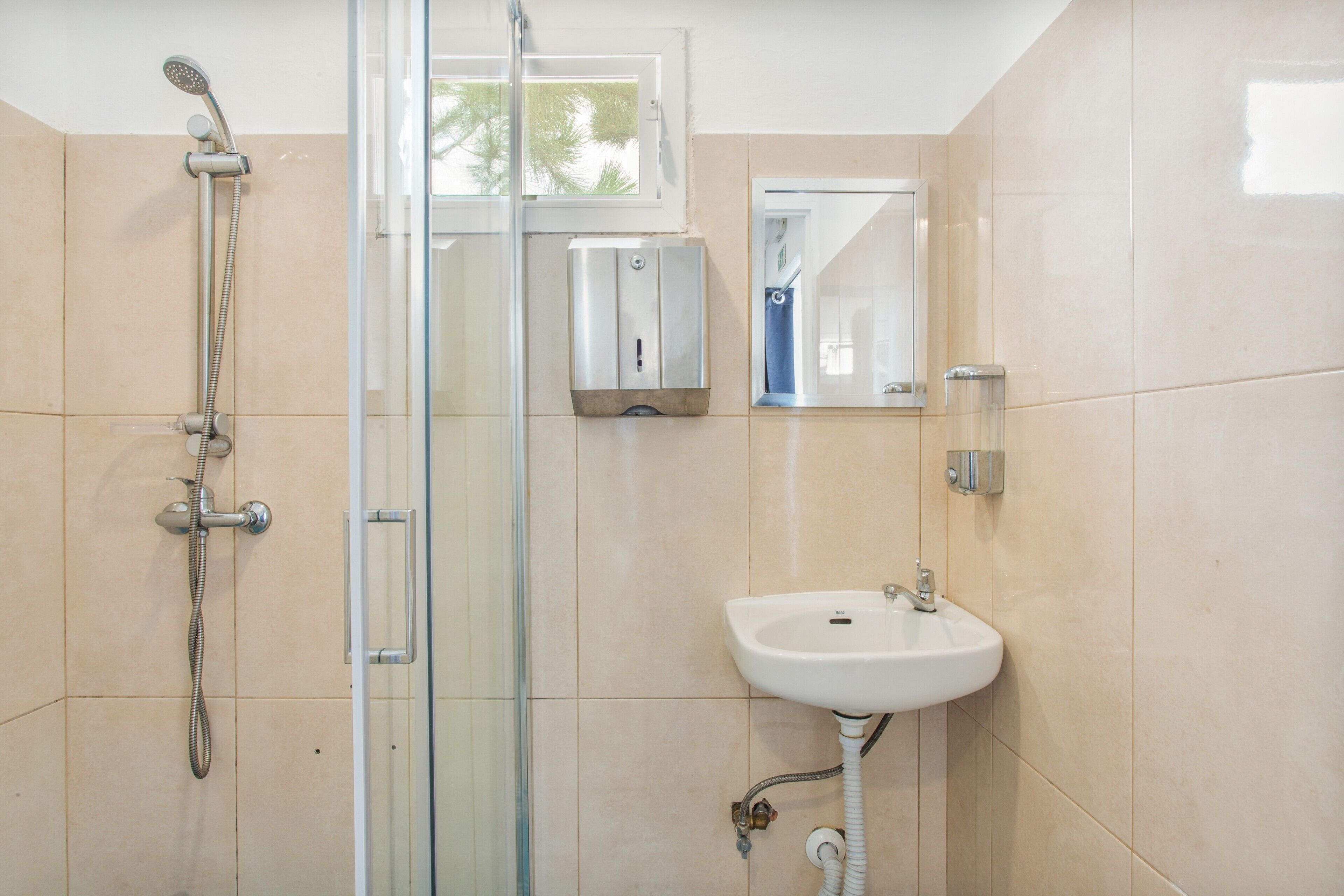 A bathroom with a glass-enclosed shower, a white sink, and a mirror.