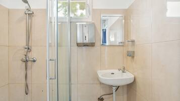 A bathroom with a glass-enclosed shower, a white sink, and a mirror.