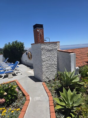 Eine Dachterrasse mit Liegestühlen, einem Backsteinsschornstein und freiem Blick auf die Landschaft.