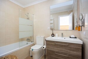 Une salle de bain moderne avec une baignoire, des toilettes, un meuble-lavabo et un grand miroir.
