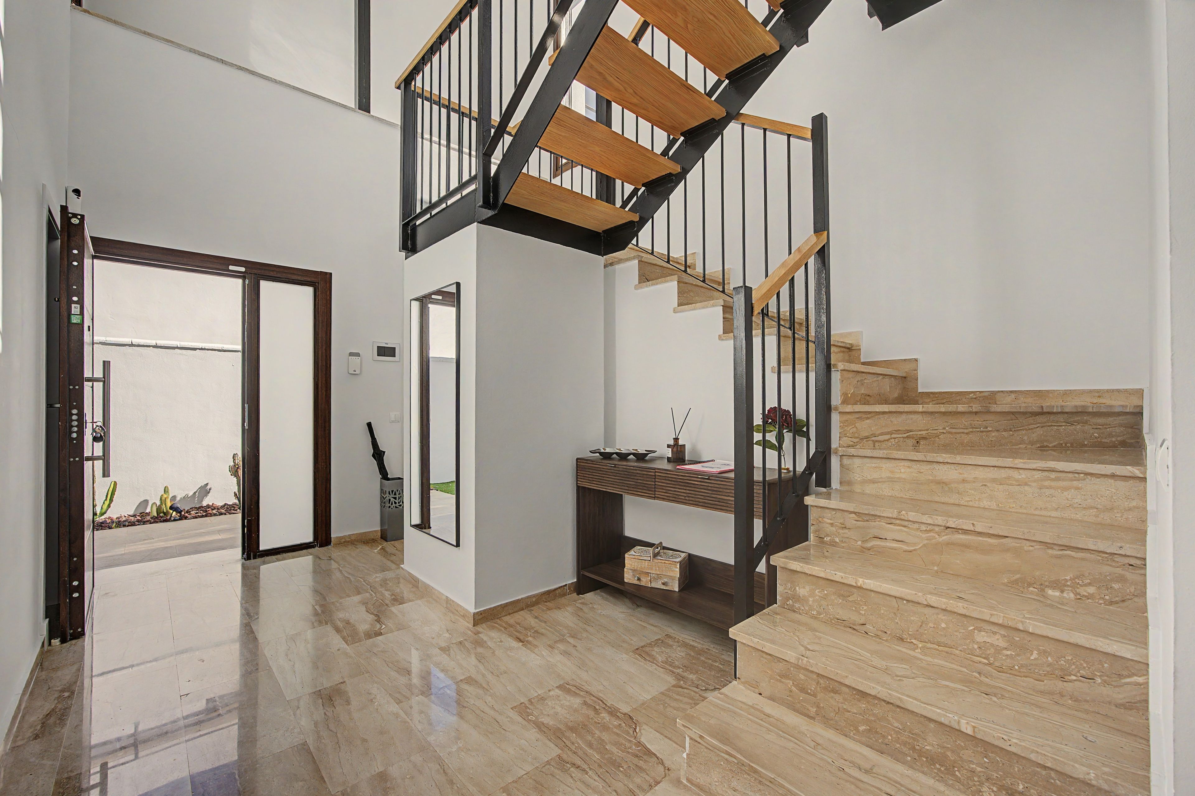 A modern interior with a marble staircase, a wooden bench, and a door leading outside.