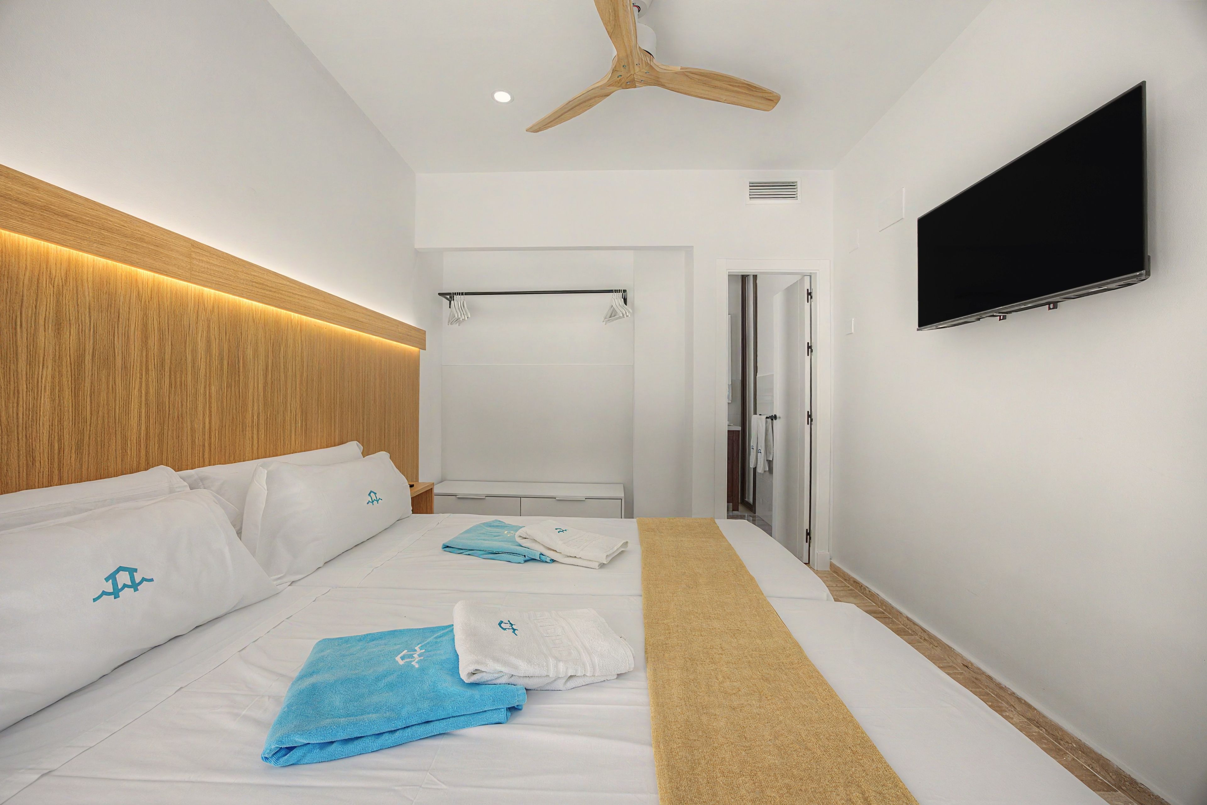 Een hotelkamer met een bed, een televisie, een plafondventilator en een douche.