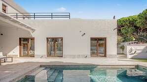 Una casa moderna con piscina, ampie finestre e un balcone.