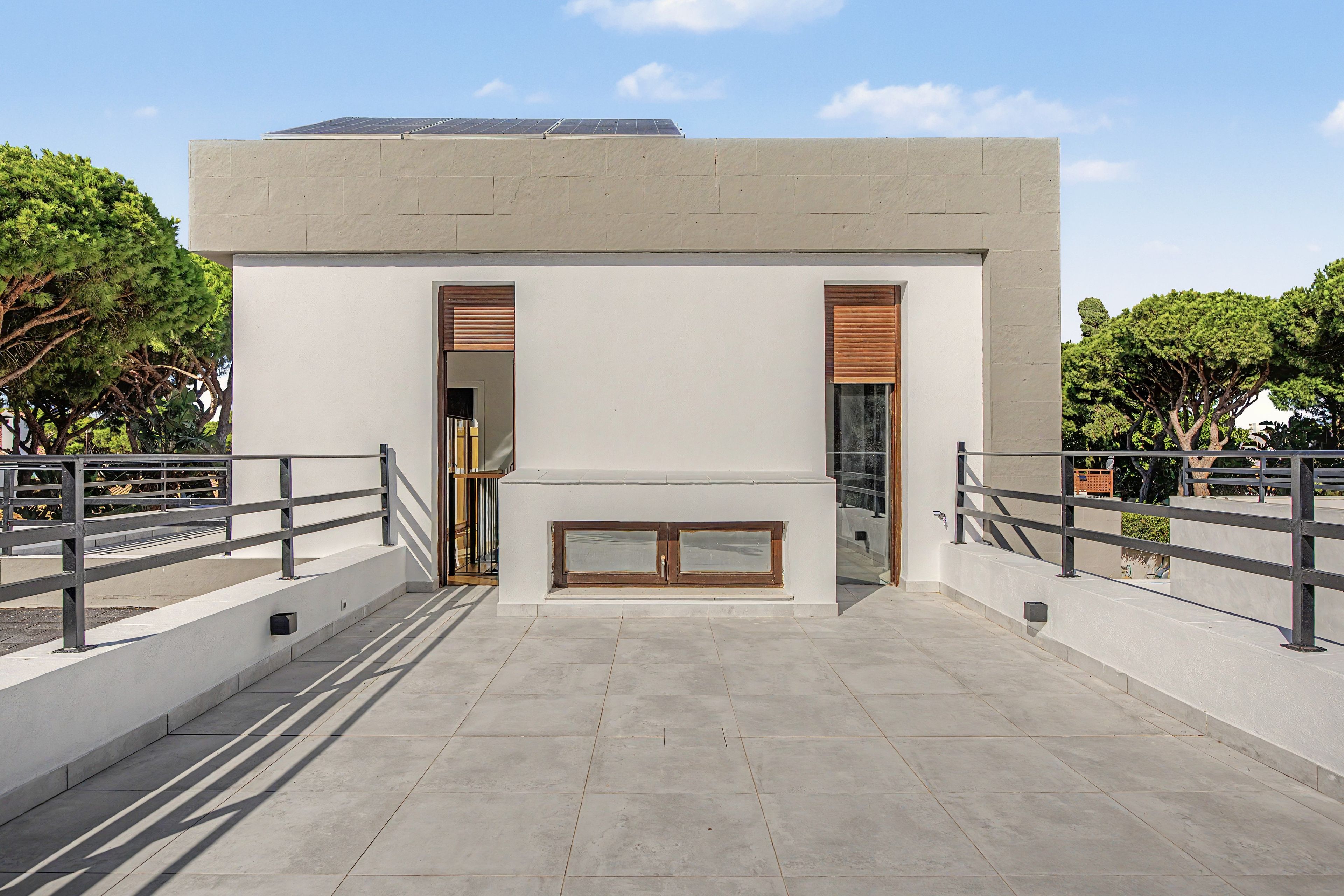 Een modern gebouw met een plat dak, grote ramen en een balkon met een metalen hekwerk.