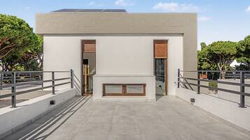 Een modern gebouw met een plat dak, grote ramen en een balkon met een metalen hekwerk.