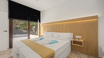 Un dormitorio moderno con cama, mesita de noche, toma de corriente y vistas al exterior.