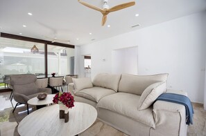 A modern living room with a beige sofa, a round coffee table, and a ceiling fan. - Villa 'Fely Sea' with Private Pool, Wi-Fi and Air Conditioning (Chiclana de la Frontera)