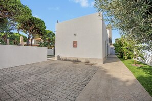 Ein gepflasterter Weg führt zu einem Gebäude mit einer Gedenktafel an der Fassade.