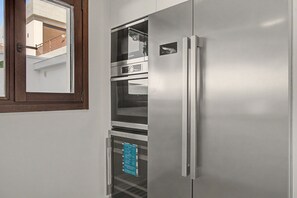Eine kleine Küche mit eingebautem Backofen und einem Edelstahl-Kühlschrank.