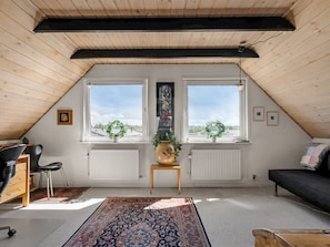 A cozy attic room with a sloped ceiling, two windows with wreaths, a radiator, a desk, a chair, a sofa, and a large rug. - "Zina" - 50m from the sea by Interhome (Blokhus)