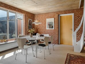 Un coin repas avec un mur en briques, une table blanche et des chaises.