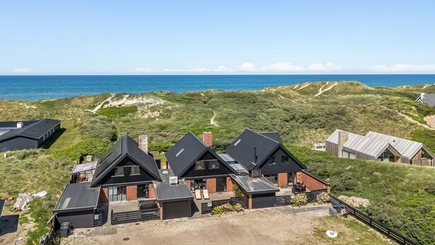 Une propriété située sur la côte, comprenant plusieurs maisons, offrant une vue dégagée sur l’océan et donnant sur un paysage de dunes.