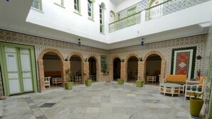 Un patio espacioso con suelo de baldosas, varios arcos y una zona de estar central.