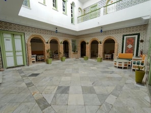 Un patio espacioso con suelo de baldosas, varios arcos y una zona de estar central.