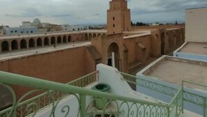 Terraza en la azotea con vistas a una torre histórica, un paseo cubierto y cielo despejado.