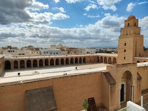 Un patio con una torre, paseos con arcos y una estructura en forma de cúpula al fondo.
