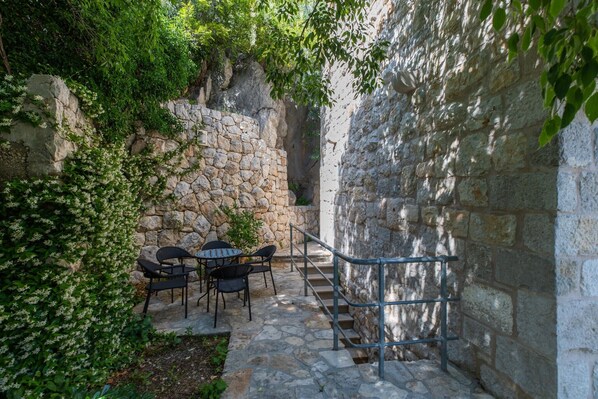 Eine Steinmauer mit Metallgeländer, eine Steintreppe und ein Tisch mit Stühlen.