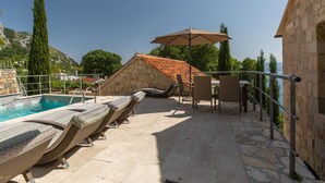 Uma área na piscina com espreguiçadeiras, uma mesa e um guarda-sol.