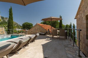 Ein Poolbereich mit Liegestühlen, einem Tisch und einem Sonnenschirm.
