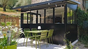 Un patio exterior moderno con una mesa, sillas, una lámpara y vistas a un edificio de piedra.
