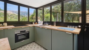Una cocina moderna con ventanas amplias, horno empotrado y encimera de madera.