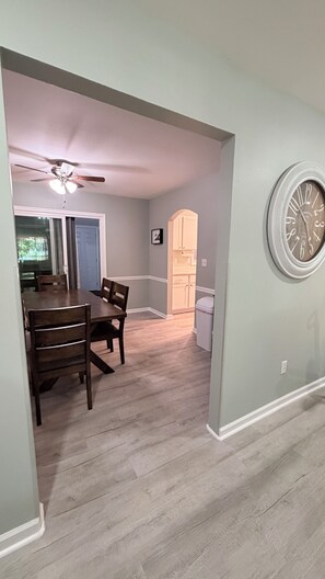A dining area with a table and chairs, a ceiling fan, and a clock on the wall.