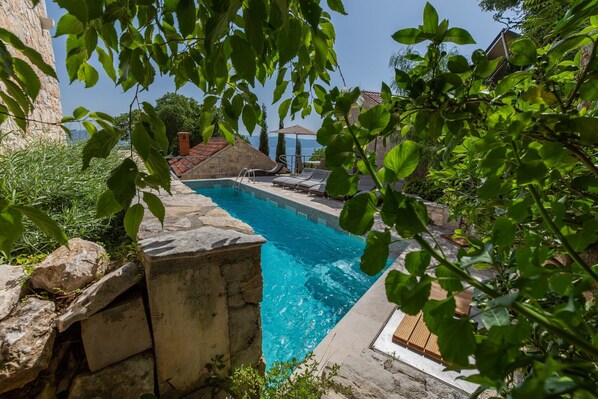 Ein Swimmingpool mit Steinwänden, einer Rutsche und Liegestühlen.