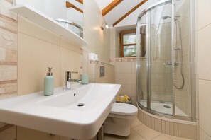 Ein Badezimmer mit einem weißen Waschbecken, einer Toilette und einer Duschkabine.