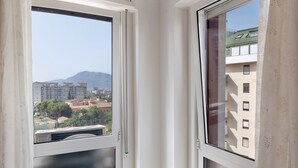 Ein Fenster mit Blick auf eine Stadtlandschaft, inklusive Gebäude und einem Berg.