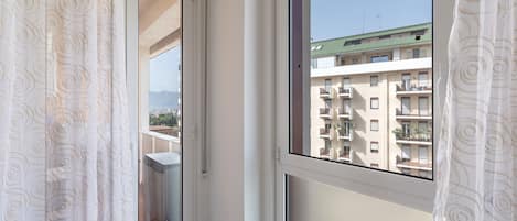 Una ventana con vista a un edificio de varios pisos y un cielo despejado.