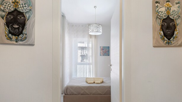 Ein Schlafzimmer mit einem Bett, einem Fenster mit Vorhängen und Bildern an den Wänden.