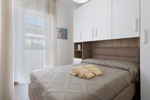 A bedroom with a bed, a window with curtains, a painting on the wall, and a wooden headboard. - 'Freedom House Palermo' Apartment with Mountain View, Wi-Fi and Air Conditioning (Palermo)
