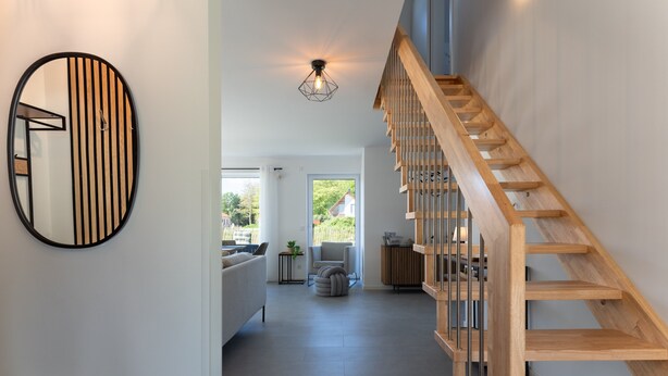 A modern interior with a wooden staircase, a round mirror, and a view to the outside. - Thatched Holiday Home 'Reetdachhus' in Klausdorf near Stralsund (Klausdorf)