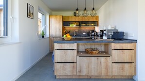 A modern kitchen with wooden cabinets, a central island, and pendant lighting. - Thatched Holiday Home 'Reetdachhus' in Klausdorf near Stralsund (Klausdorf)