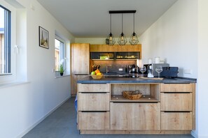 Eine moderne Küche mit Holzausstattung, einer zentralen Kochinsel und Pendelleuchten.