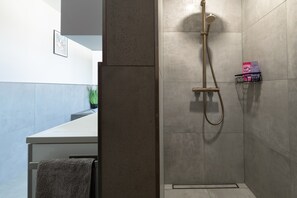 Ein Badezimmer mit Dusche, Handtuchhalter und einer kleinen Ablage für Pflegeprodukte.