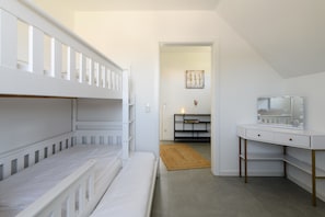 A bedroom with bunk beds, a desk with a mirror, and a small rug.