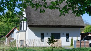 A white house with a thatched roof, a wooden fence, and a small garden. - Thatched Holiday Home 'Reetdachhus' in Klausdorf near Stralsund (Klausdorf)