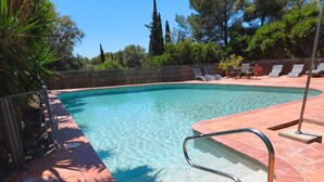 Una piscina trasparente con gradini piastrellati e un corrimano in metallo.