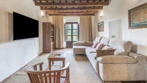 Un soggiorno con un divano, un tavolo in legno, una TV a parete e una libreria.