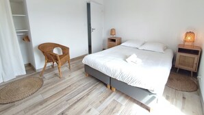 A bedroom with a bed, a chair, a wardrobe, and a hanging light fixture. - Le 4 Pors Carn – walk to the beach, peaceful, sea view (Penmarch)