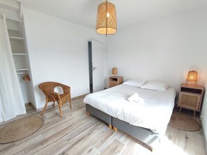 Quarto com cama, cadeira, guarda-roupa e luminária suspensa.